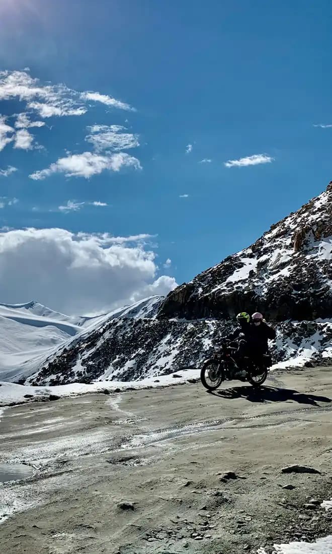 Indian Rides – High-Altitude Motorcycle Adventure in Ladakh Motorcycle riding through snowy mountain landscapes in Ladakh